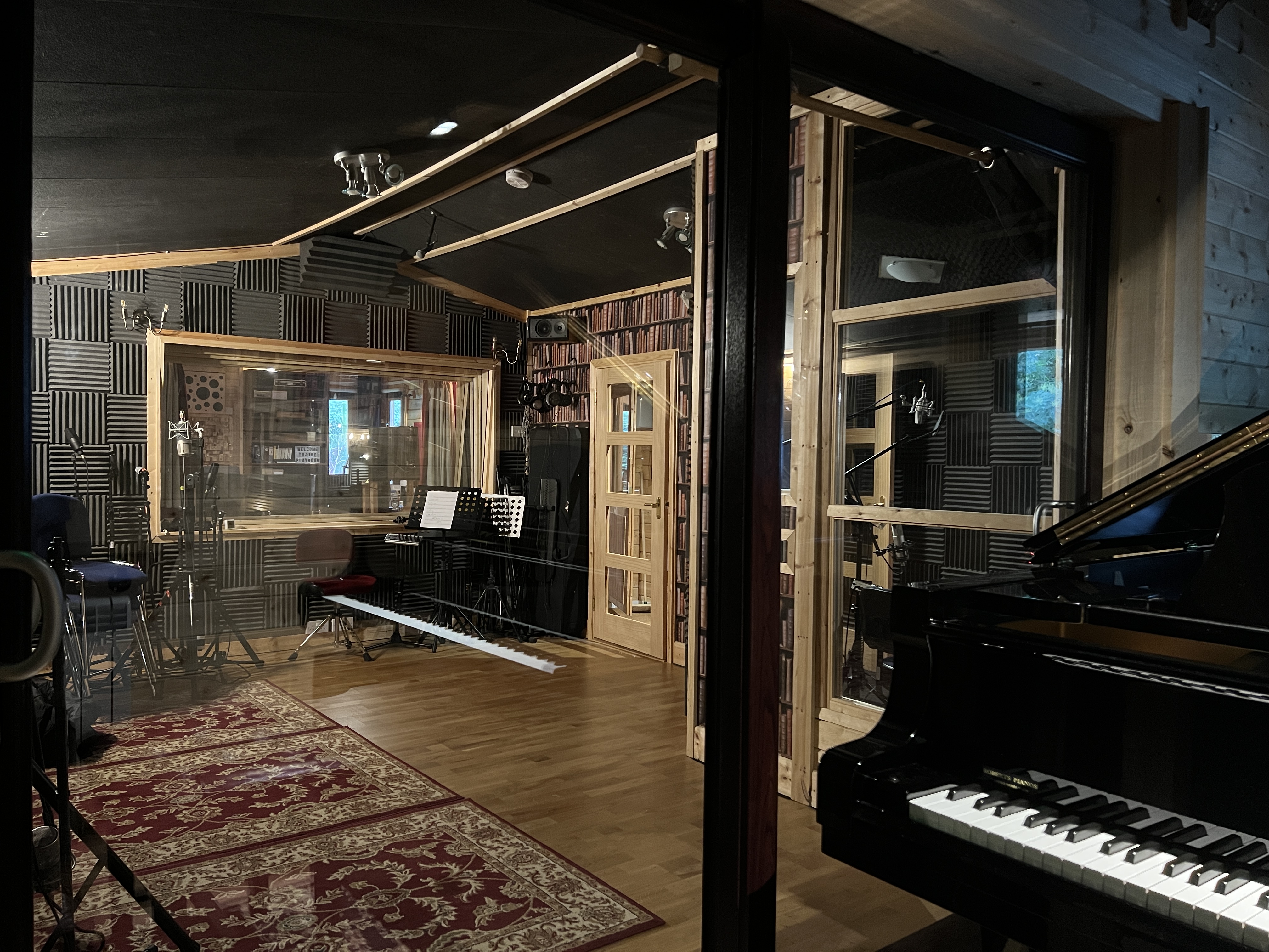 Interior view of The Playroom studio in Arundel, showcasing a spacious vocal booth, live room, Yamaha pianos, and soundproofing features.